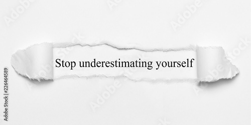 Stop underestimating yourself on white torn paper photo