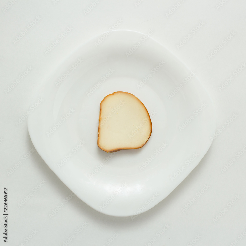 Slices and piece of cheese on plate on white background, top view Slices and piece of cheese on plate on white background, top view