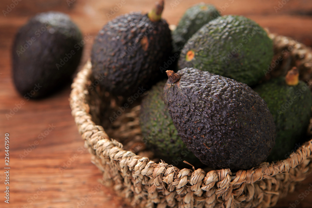 Hass avocado in seagrass basket on rustic wooden table. Healthy fruits concept. Selective focus and free space for text. Hass avocado in seagrass basket on rustic wooden table. Healthy fruits concept. Selective focus and free space for text.