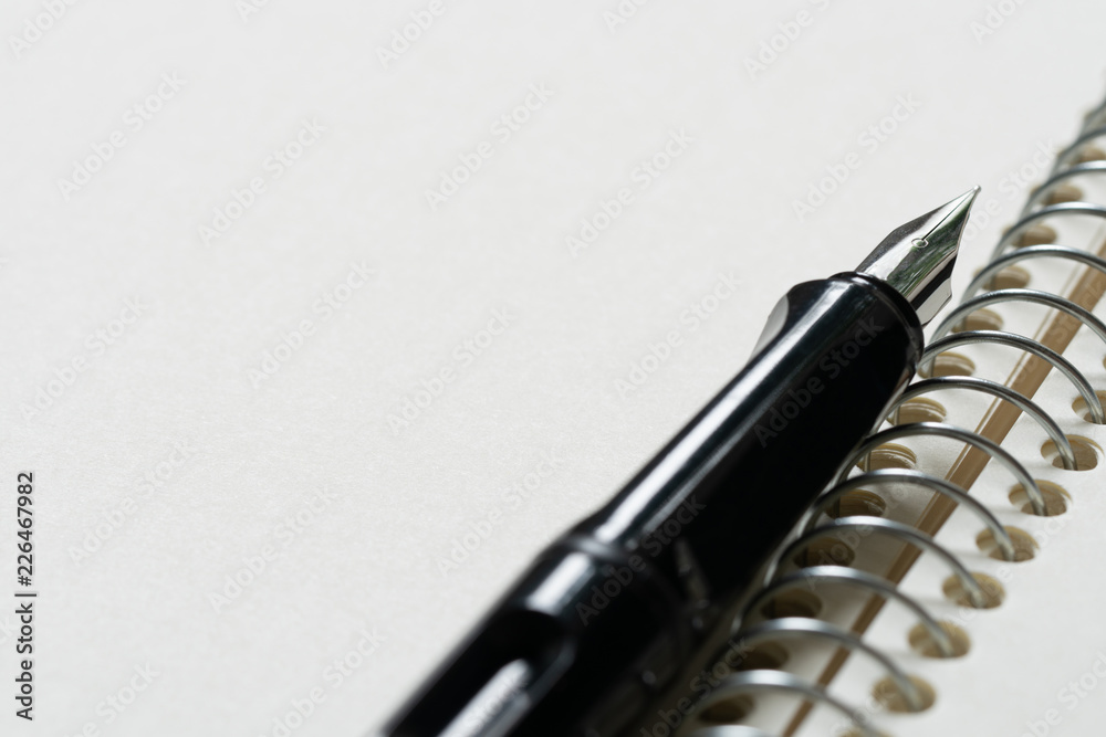 Fountain pen placed on the white paper opaque. Communication to business transactions, education, work, suitable as a background image. Fountain pen placed on the white paper opaque. Communication to business transactions, education, work, suitable as a background image.