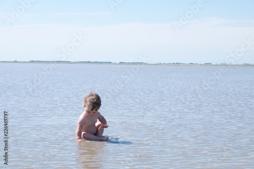 Sitting baby among the lake at summer. Salt shallow lake in Russia. Loneliness  concept in big world © aynur_sh