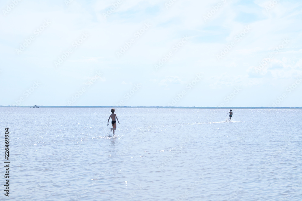 Running children on the surface of lake at summer. Salt shallow lake in Russia. Loneliness  concept in big world