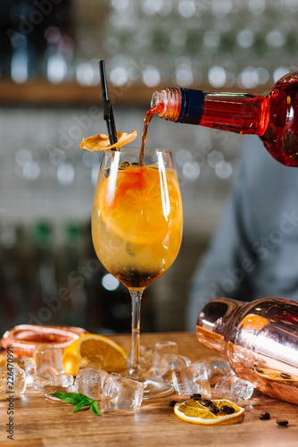 Orange cocktail with lemon and ice in glass at the bar background