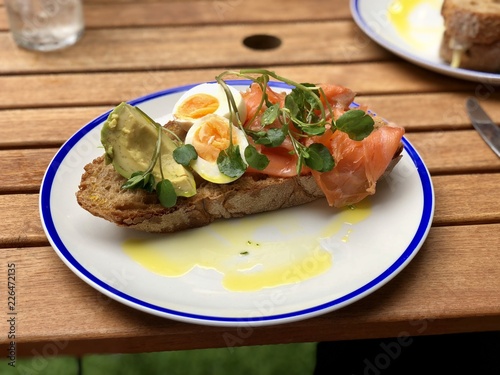 Smoked salmon, soft boiled egg and avocado on sourdough toast with watercress and police oil dressing