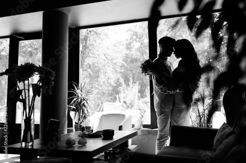 Black and white picture of newlyweds kissing in dark cafe