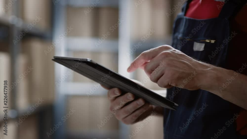 Close-up on a Man's Hands Using Digital Tablet Computer while Standing in the Warehouse.