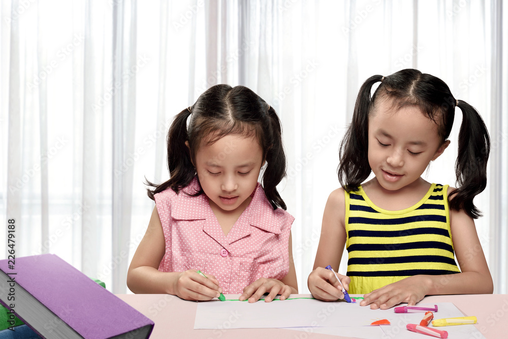 Two asian girl drawing with colorful crayon Two asian girl drawing with colorful crayon