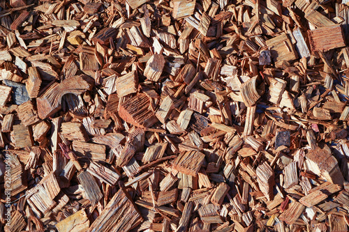 A pile of wood sawdust lies on the ground in sunny weather. 