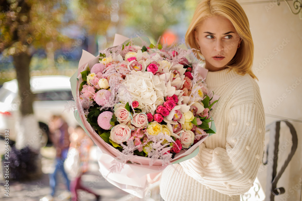 Fototapeta premium Girl holding a beautiful bouquet of different pink flowers