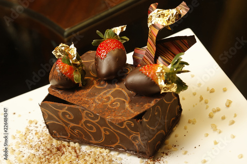 Fotografi Chocolate dessert with chopped nuts and strawberries covered in liquid chocolate