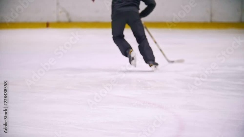 Hockey player leads the puck and running on the ice during the hockey match. View from the back photo