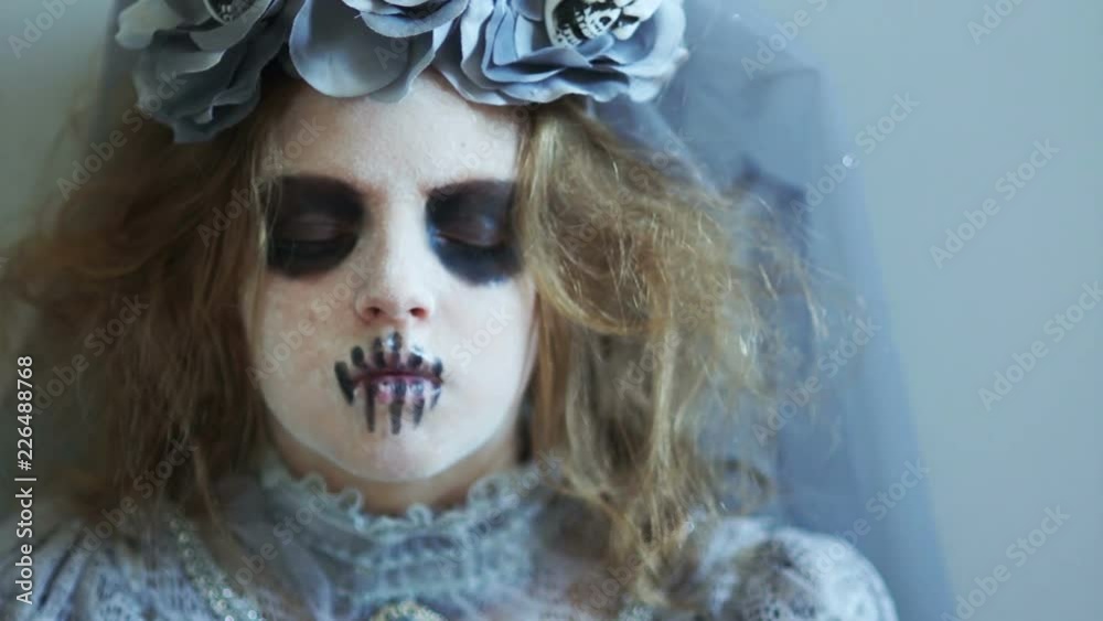 A child dressed as Halloween looks into the camera and laughs. The girl in the makeup of the dead. The costume of the bride of Dracula. Celebration of the day of the dead A child dressed as Halloween looks into the camera and laughs. The girl in the makeup of the dead. The costume of the bride of Dracula. Celebration of the day of the dead