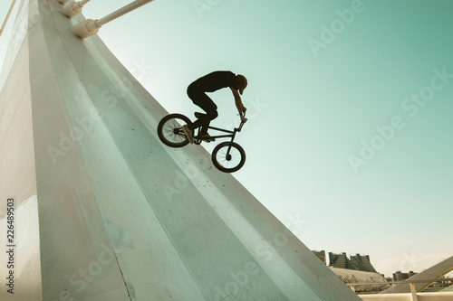Young man with a bmx bike riding down the street
