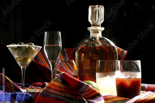 In front of the image a glass of brandy accompanied by a martini glass with olives and tulip cup. Brandy is a spirit produced by distilling wine and is typically drunk as an after-dinner digestif.