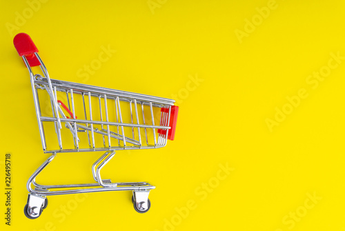 Shopping trolley on colorful background with copy space and selective focus