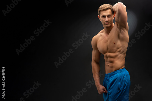 Sports wallpaper on dark background. Power athletic guy bodybuilder. Sport nutrition banner. © Anton