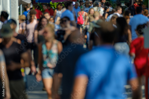Unidentified crowd of people walking on the street at sunny day time © Anton Gvozdikov