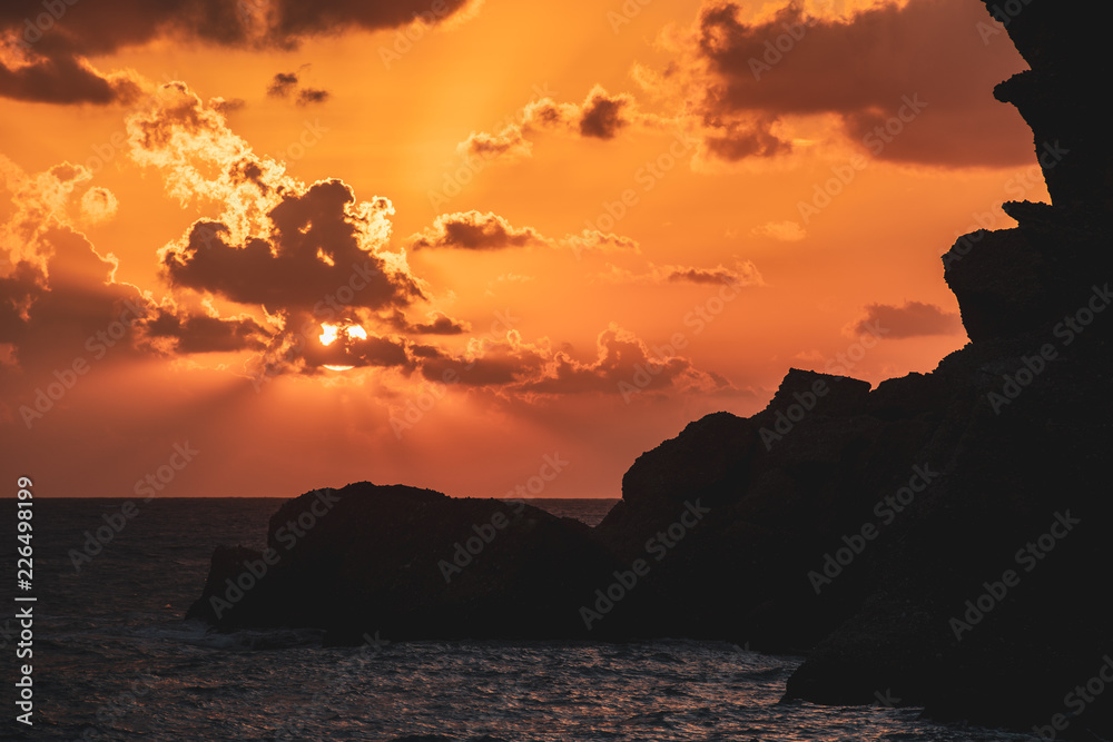 Silhouette eines Felsens am Meer mit untergehender Sonne