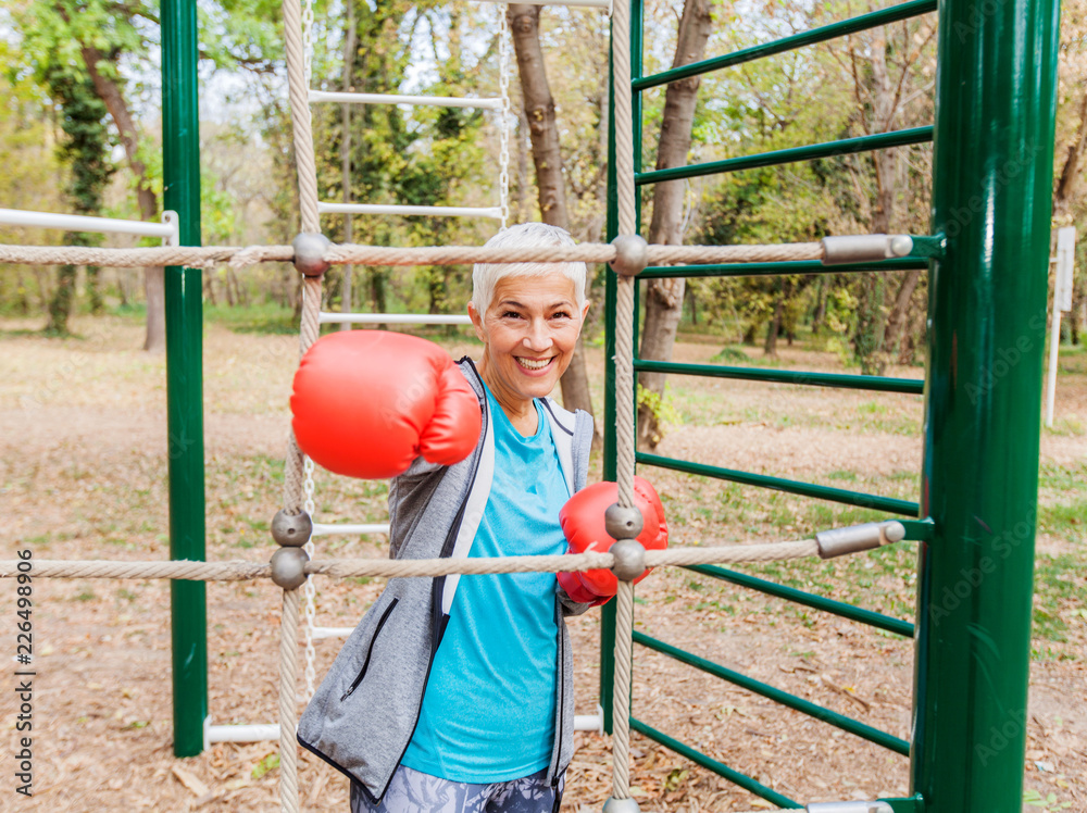 Obraz premium Happy Fit Senior Woman With Boxing Glove At Outdoor Gym