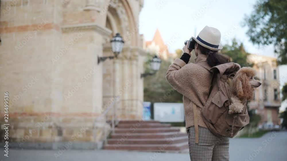 Woman traveler with dog in the backpack making pictures with a camera while traveling. Woman traveler with dog in the backpack making pictures with a camera while traveling.