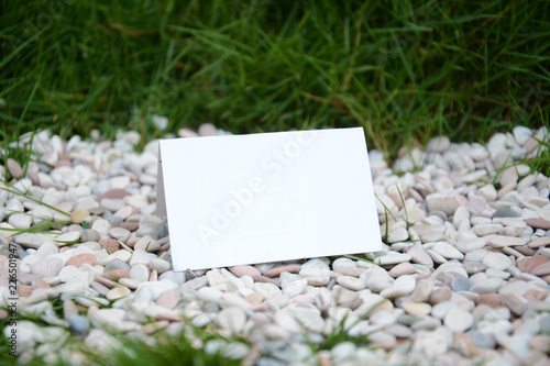 Blank white folded paper on the gravels and grasses