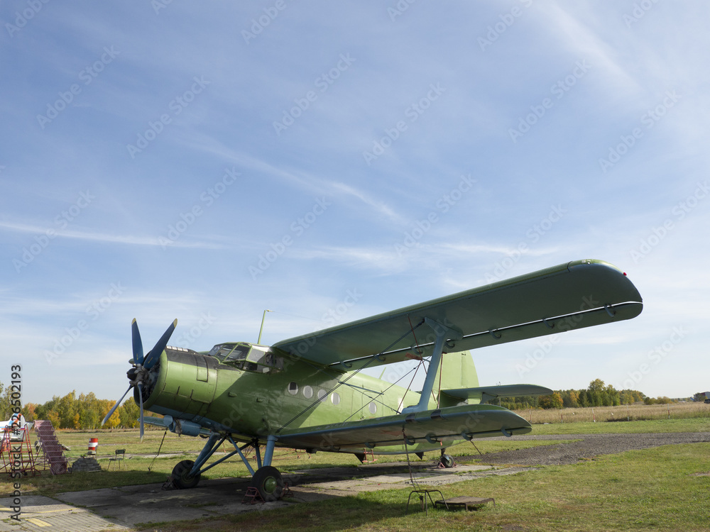 View of classic airplane on the grassy airfield; aircraft after the flight with cases on propellers and other elements; green military aircraft on the runway; historical heritage of Russia View of classic airplane on the grassy airfield; aircraft after the flight with cases on propellers and other elements; green military aircraft on the runway; historical heritage of Russia