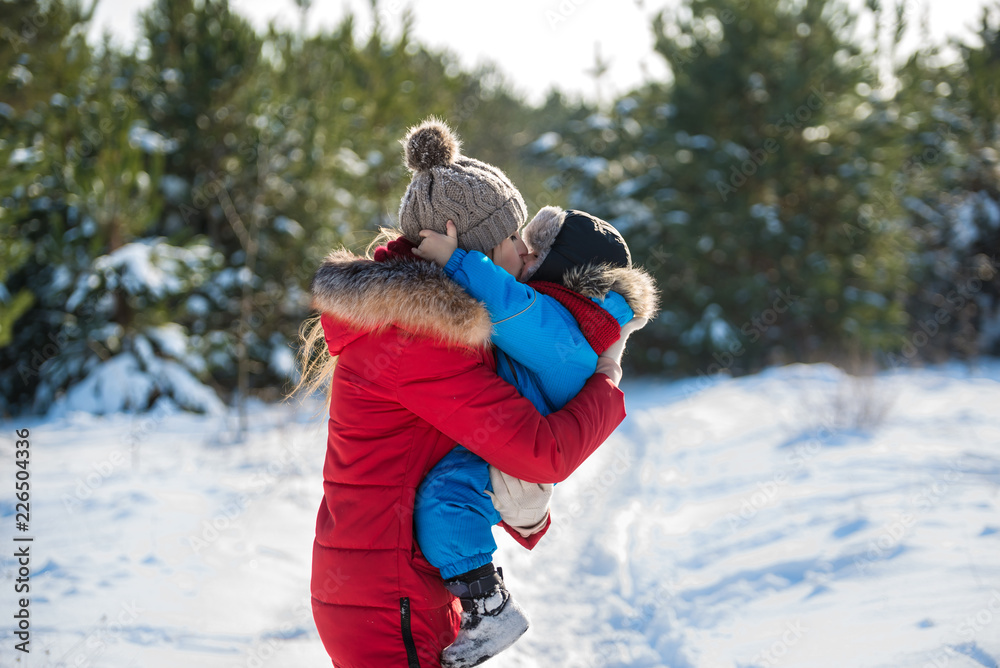 Happy young mother and her son have fun in winter. Play in snow