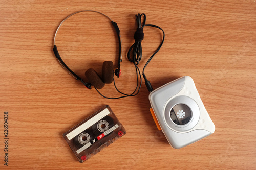 Old portable cassette tape player and headphones on wooden floor
