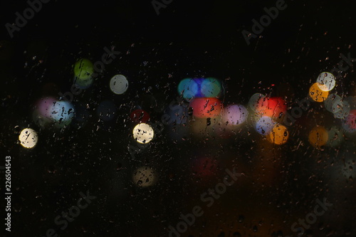 Fototapeta Naklejka Na Ścianę i Meble -  Color lights on the rainy dark window glass