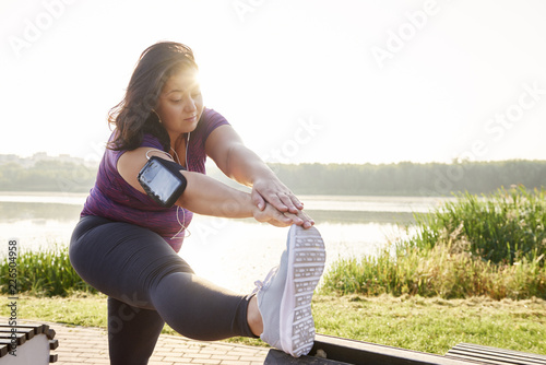 Young woman stretching her legs before running photo