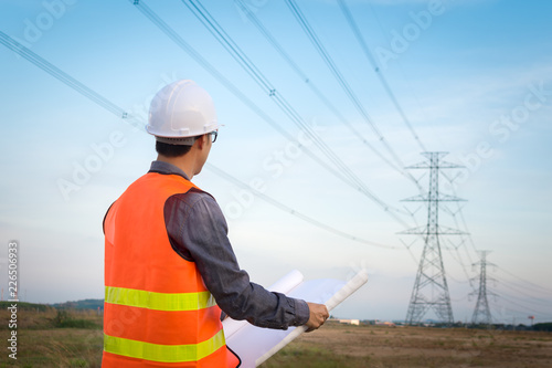 Engineering worker checking location site near to High voltage tower.