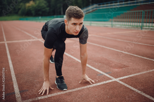 Young man athlete training stadium. Runners feet in athletic running track. © Parilov