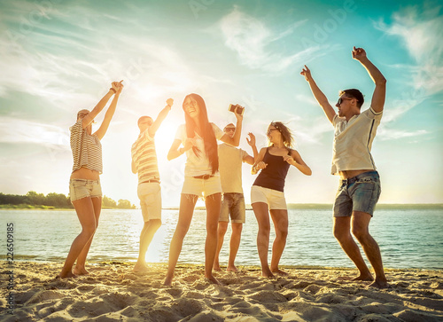 Friends funny dance on the beach under sunset sunlight. Sunny day photo