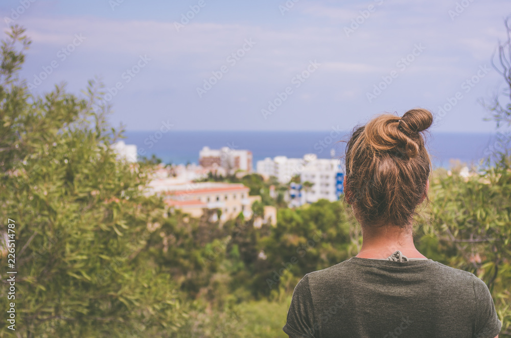 Obraz premium A woman stares into the distance to the sea horizon and the city in front of him