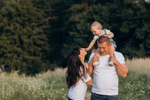Konstfotografi Warm hugs of young parents and their little daughter standing in the summer fiel