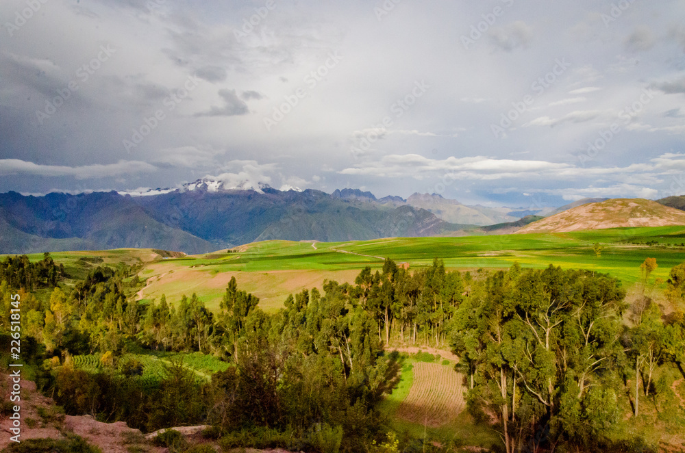 Green fields planted with clouds and mountains on the road to Moray, Peru