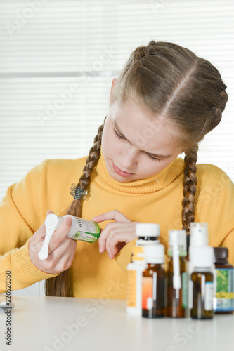 Portrait of a cute little girl taking medicine at home