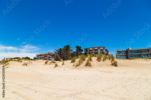 Fototapeta Naklejka Na Ścianę i Meble -  Mar de las Pampas. Argentina. Panoramic view of a beautiful beach with apartments buildings at the background. The sky is clear and intense blue.