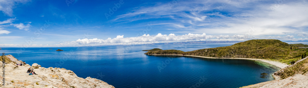 Panoramic on Isla del Sol with a blue Titikaka Lake, stones, an island and a few turists on a sunny day