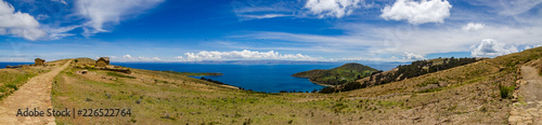 Panoramic on Isla del Sol with a road made of stones, the Titikaka Lake and small constructions on a sunny day