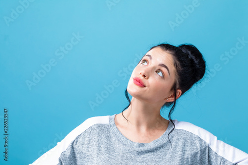 Slika na platnu Young woman looking upwards on a solid background