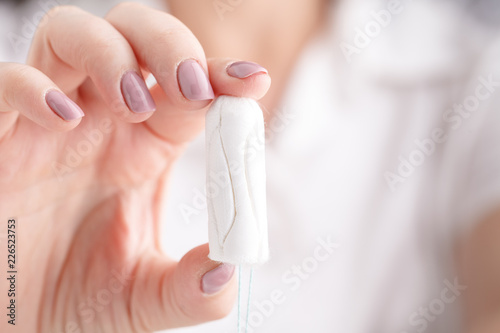 Girl holding tampon during the monthly cycle. Young woman hands holding menstruation cotton tampon