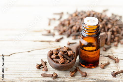 clove essential oil in the glass bottle, on the wooden board photo