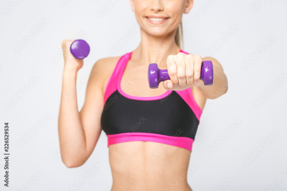 Close-uo of happy young fitness woman lifting dumbbells smiling and energetic. Isolated over white background. Close-uo of happy young fitness woman lifting dumbbells smiling and energetic. Isolated over white background.