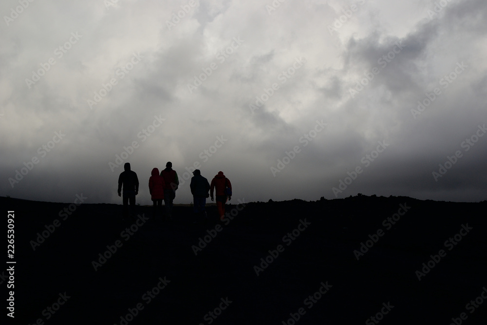Five people silhouettes on gloomy sky