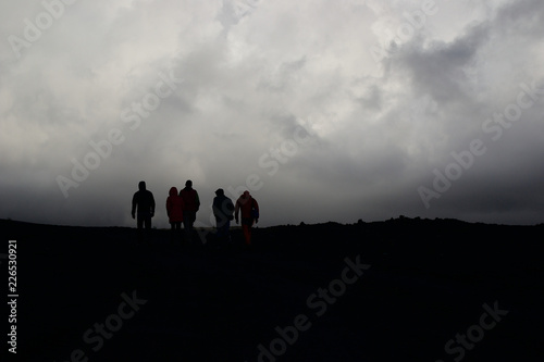 Five people silhouettes on gloomy sky