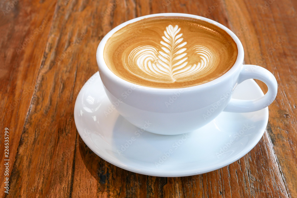 Hot coffee latte cappuccino cup with beautiful 'rosetta' latte art milk foam on rustic wood table background. Hot coffee latte cappuccino cup with beautiful 'rosetta' latte art milk foam on rustic wood table background.