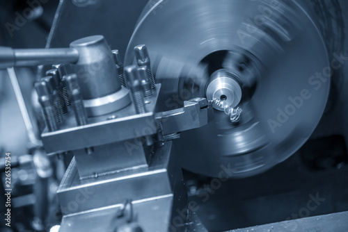The operation of lathe machine cutting the steel shaft in the light blue scene.