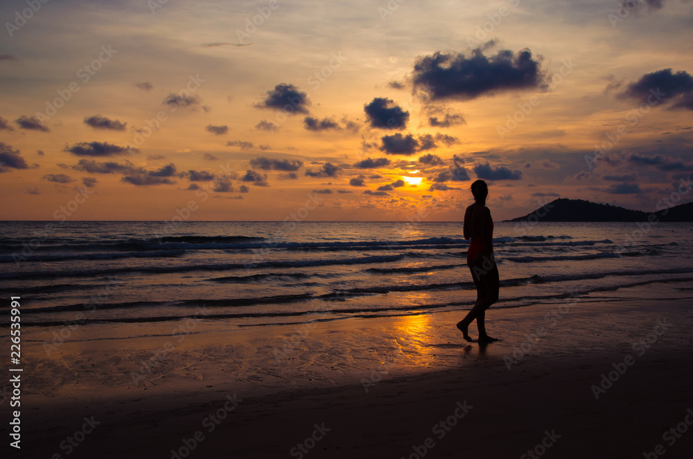 silhouette sunset with girl walking on beach