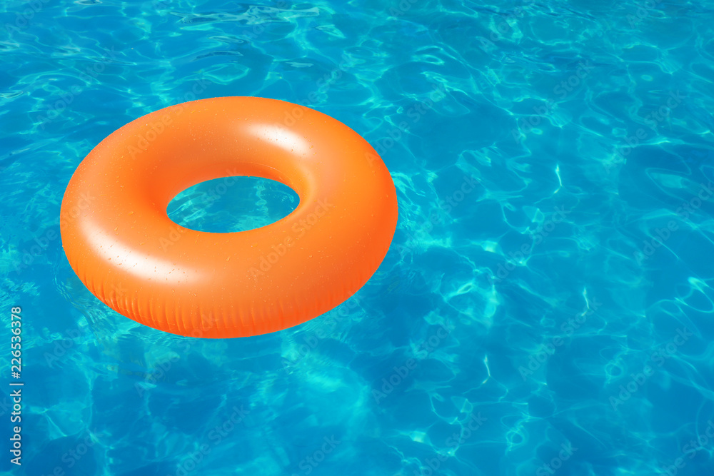 Fototapeta premium Inflatable ring floating in swimming pool on sunny day. Space for text